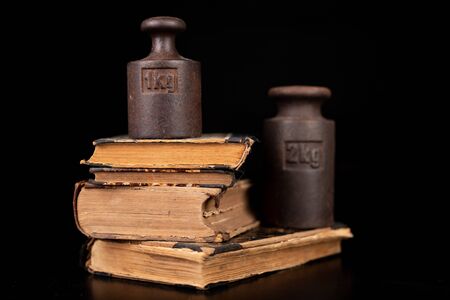 Old kilo weights on books. Old books and weighing machines. Dark background.