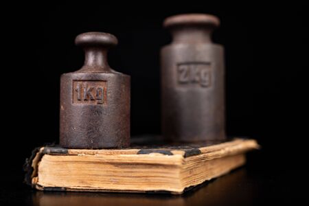 Old kilo weights on books. Old books and weighing machines. Dark background.の写真素材