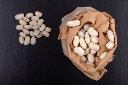 Bean in paper bags on the kitchen table. Food ingredients used in the kitchen. Dark background.