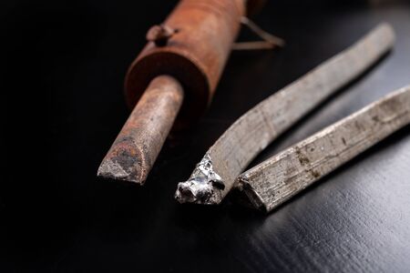 A large soldering iron and soldering accessories on a workshop table. Connecting sheets using...