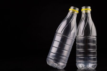Plastic bottle after a food drink. Disposable packaging on a dark table. Black background.の写真素材