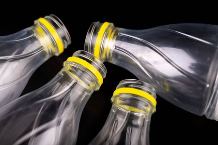 Plastic bottle after a food drink. Disposable packaging on a dark table. Black background.