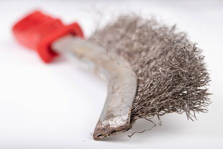A brush with metal prongs on a white table. Tools for the slusier to clean the material. Light...