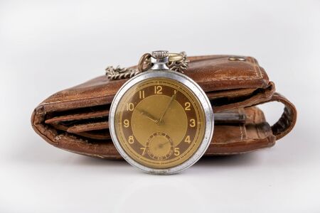 Leather wallet and an old watch on a white table. Personal documents in leather cover. Light...