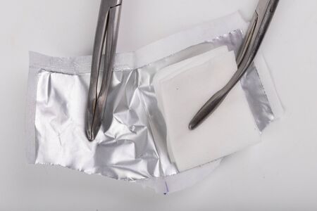 Cotton swab soaked in alcohol in metal medical pliers. Doctor's accessories for disinfection. Light background.の写真素材