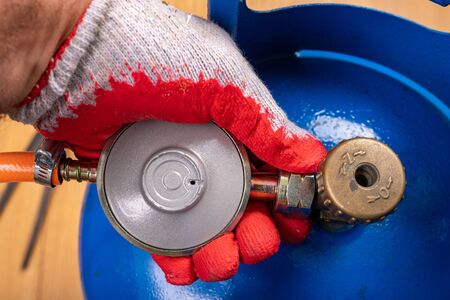 Reducer and gas cylinder for domestic use. Replacing the gas cylinder in the home kitchen. Place - households.の写真素材