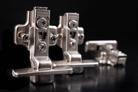 Metal furniture hinges with hydraulic brake. Furniture accessories for the production of furniture on a dark table. Black background.の写真素材