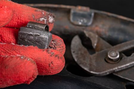 Lead weights on rim and tongs. Accessories for the vulcanizer in the workshop. Dark background.の写真素材