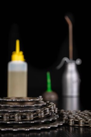 Oiling the bicycle chain with an oil can on the workshop table. Servicing of bicycle parts. Dark background.の写真素材