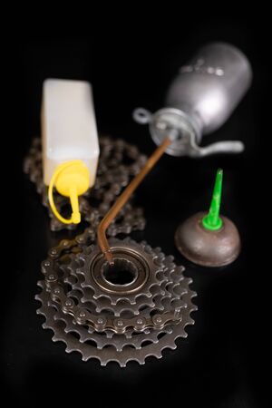 Oiling the bicycle chain with an oil can on the workshop table. Servicing of bicycle parts. Dark background.の写真素材