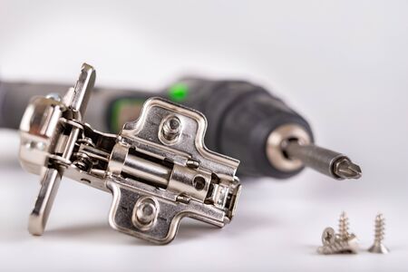 Furniture hinges on a white table. Furniture accessories for carpenters. Light background.