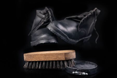 Black shoe polish, brush and shoes on the table. Accessories for cleaning leather footwear. Dark background.の写真素材