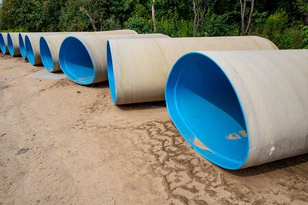 New sewer pipes prepared for assembly. Material laid out at the construction site. Summer season.