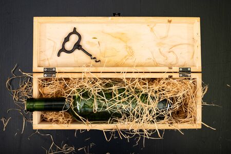 A bottle of wine in a wooden box. A tasty alcoholic drink in an elegant package. Dark background.の写真素材