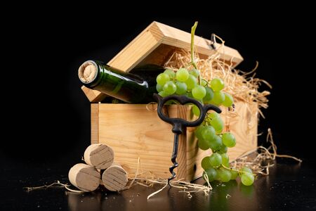A bottle of wine in a wooden box. A tasty alcoholic drink in an elegant package. Dark background.の写真素材