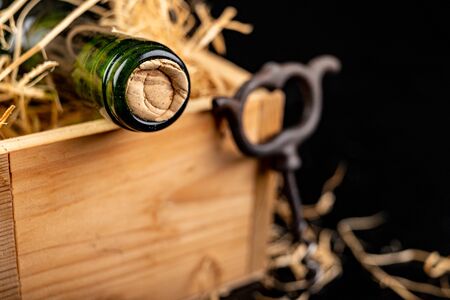 A bottle of wine in a wooden box. A tasty alcoholic drink in an elegant package. Dark background.の写真素材