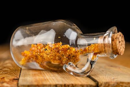 Small raw amber in a glass bottle on a wooden table. A precious find from the coast of Central...