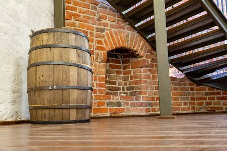 Old wooden barrel against the white wall. Exhibit in the museum. Light background.