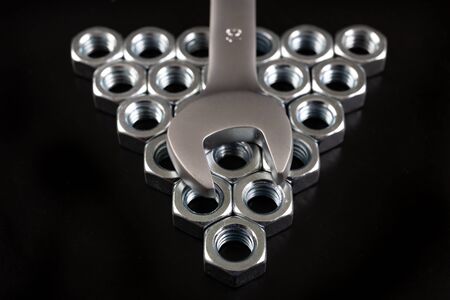Nickel-plated nuts and wrenches on a workshop table. Tools in a mechanical workshop. Dark...