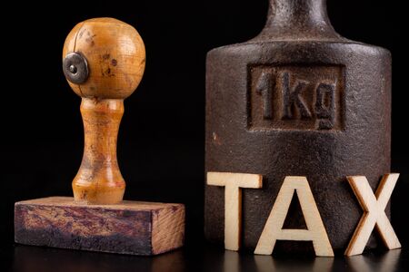 Inscription tax and old weight 1 kilogram. Stamp and store accessories on a dark table. Black background.の写真素材