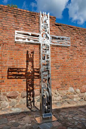 Starogard Gdanski, pomorskie / Poland-September, 19,2019: A metal cross standing against a red brick wall. Old museum buildings in Central Europe. Autumn season.のeditorial素材