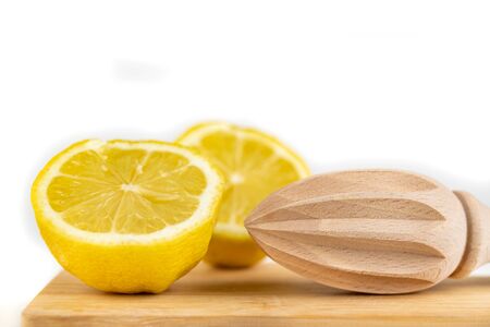 Lemon squeezer on a kitchen wooden board. Fresh lemon juice. Light background.の写真素材