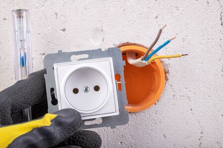 Installation of the electric socket in a rough wall. Installation of a new electrical network at home. Light background.の写真素材