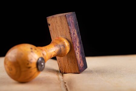 Old wooden rubber stamp on the book. Office accessories used in the office. Dark background.