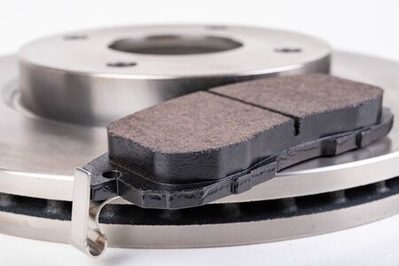 Steel brake discs and brake pads for a passenger car. New spare parts for car repairs. White...