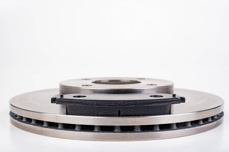 Steel brake discs and brake pads for a passenger car. New spare parts for car repairs. White...