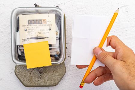Electricity meter and white paper in hand. A device for measuring the consumption of electric...