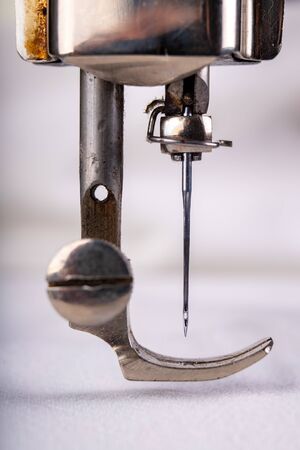Old sewing machine and white material on a dark table. An antique device for small housework. Dark...