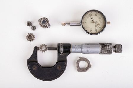Micrometer, caliper and gear wheels for measurements. Workshop accessories. Light background.