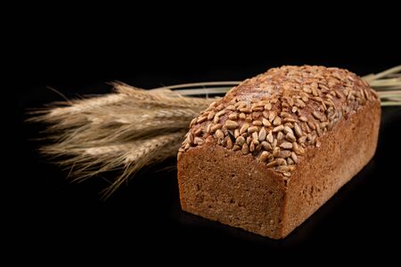 Tasty dark bread with sunflower and dry ears of wheat. Ingredients for making sandwiches on a dark...