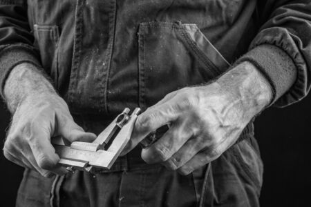 Employee in protective work safety clothing with Caliper. Occupational safety and health accessories for employees and measuring tools. Dark background.の写真素材