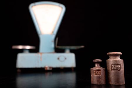 The old weight to weigh commodities from the communist era. Shop accessories on a stolen table. Dark...