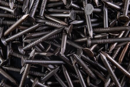 Black steel nails on a workbench. Furniture accessories in the workshop. Dark background.の写真素材