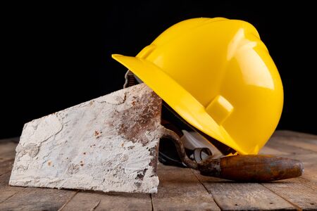 Protective helmet and tools for bricklayer. Work accessories for production workers. Dark...