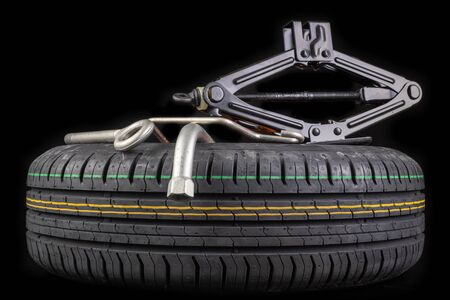 Spare wheel with a set of keys. Spare wheel replacement accessories for passenger cars. Dark background.の写真素材