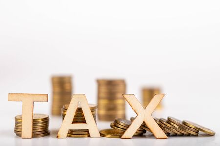TAX inscription made of wooden letters on coin posts. Symbol of tax collection from the public. Light background.の写真素材