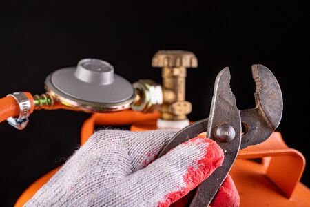 Gas cylinder and propane-butane gas reducer. Installation of a special hose for a metal cylinder. Dark background.の写真素材