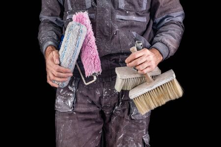 Painter holding a wall brush in his hand. Accessories for small home repairs. Dark background.の写真素材