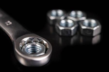 Nickel-plated wrench and nut. Workshop accessories needed for mounting mechanical parts. Dark background.の写真素材