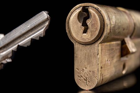 A old door lock on a dark background. A patent and keys to secure the front door. A black background.の写真素材
