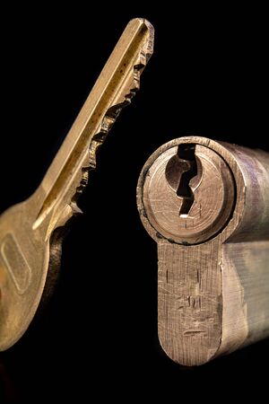 A old door lock on a dark background. A patent and keys to secure the front door. A black...