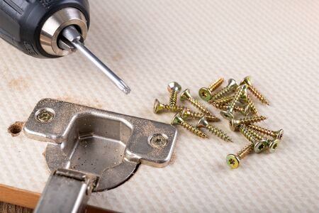 Replacement and assembly of furniture hinges. Small carpentry work in the home workshop Dark...