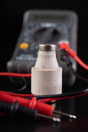 Electric meter and ceramic fuse. A device for measuring electric current and checking components. Dark background.の写真素材