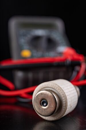 Electric meter and ceramic fuse. A device for measuring electric current and checking components. Dark background.の写真素材