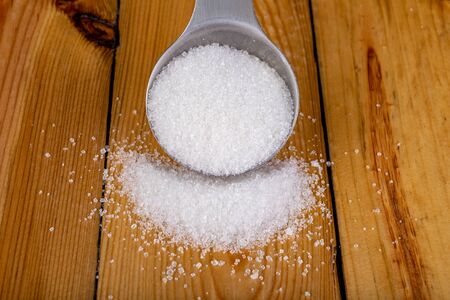 White sugar in the home kitchen. Sweetener for kitchen dishes on a wooden table. Dark background.の写真素材