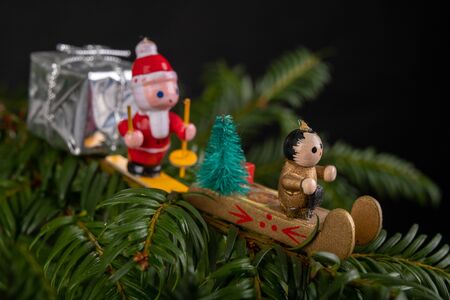 Christmas decorations on the green tree. Tinsels hung on a spruce twig. Dark background.